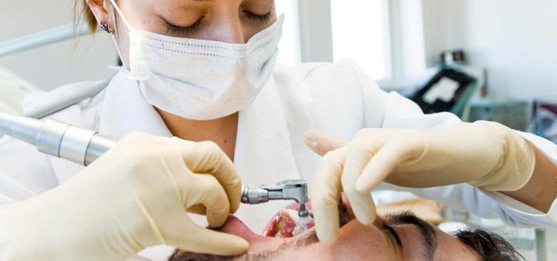 Female dentist treating man teeth.