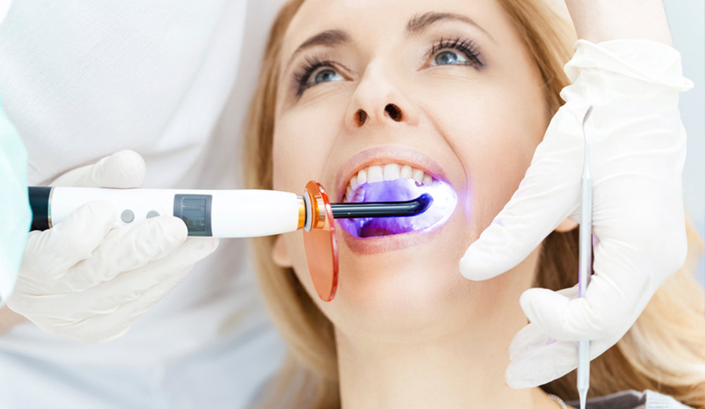 Woman having laser teeth whitening treatment.