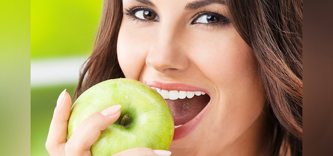 Woman eating green apple with her dental implant.