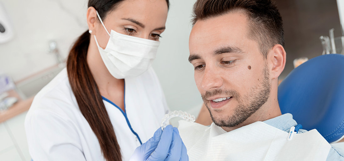 Female dentist showing her the Invisalign to male patient.